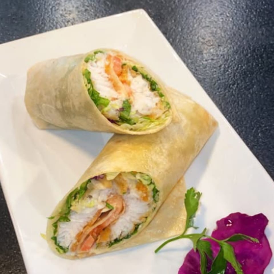 Two Havana Heights wraps filled with chicken, lettuce, and tomatoes, garnished with purple cabbage and parsley.